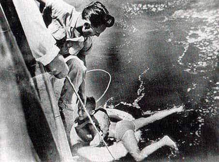 Clad only in a lifejacket and swim trunks, Roger Woodward, 7, clings to a life ring thrown from the Maid of the Mist II as he is pulled to safety by deckhand John Hopkins.