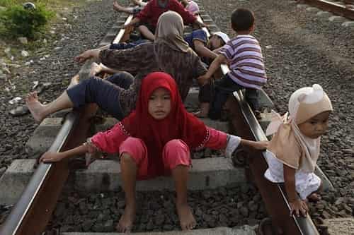 Villagers lie on a railway track and wait for a train to rattle by for electricity therapy in Rawa Buaya, Jakarta, Indonesia