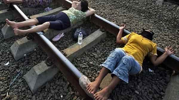 Villagers lie on a railway track and wait for a train to rattle by for electricity therapy in Rawa Buaya, Jakarta, Indonesia